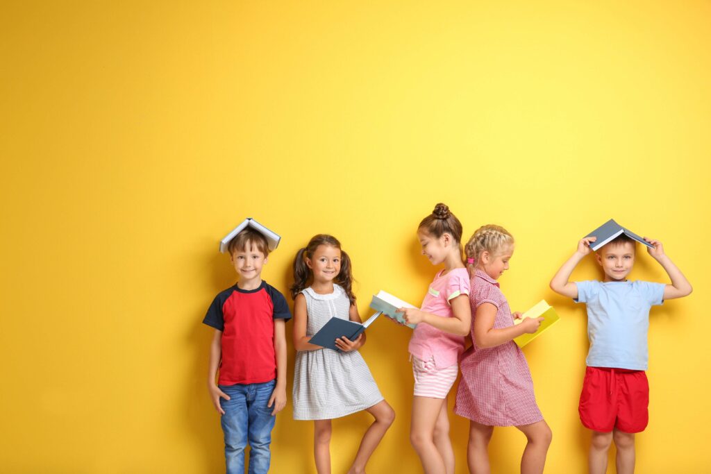 Cute little children with books on color background
